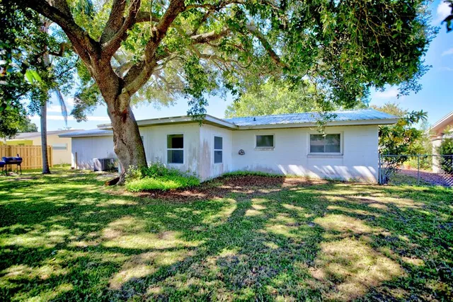 a backyard of a house with plants and large tree