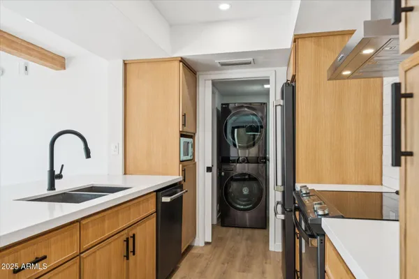 a kitchen with stainless steel appliances granite countertop a refrigerator a stove and a sink with wooden floor