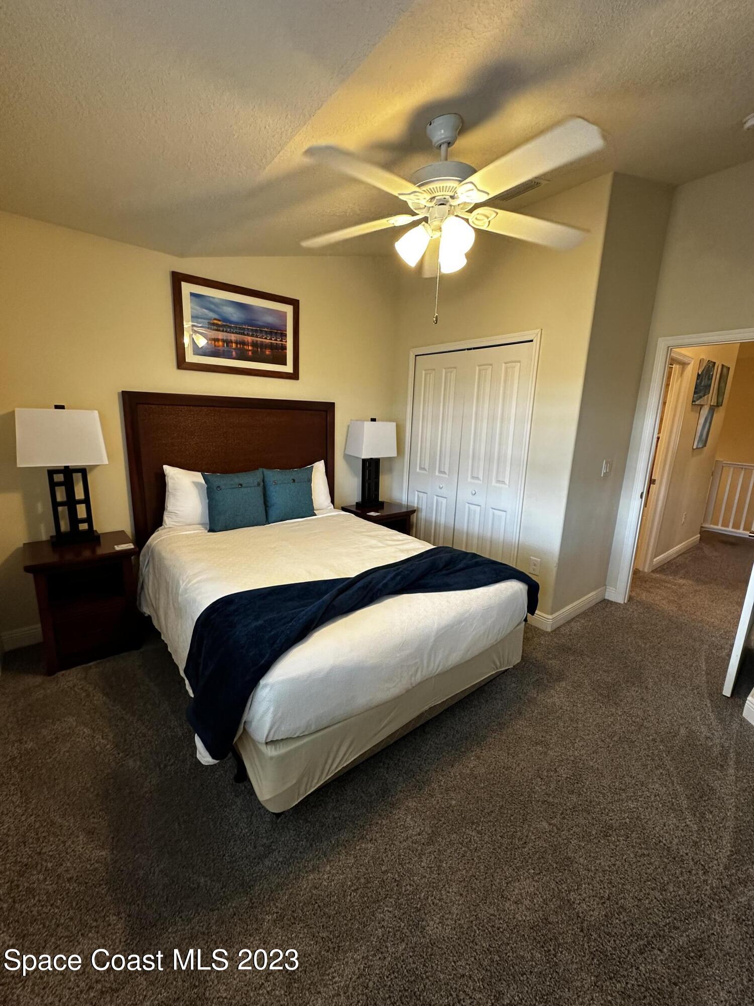 103 Parrotfish Lane, Unit 101 Merritt Island, FL 32953 - Photo 18 of 19 a bedroom with a bed and a chandelier