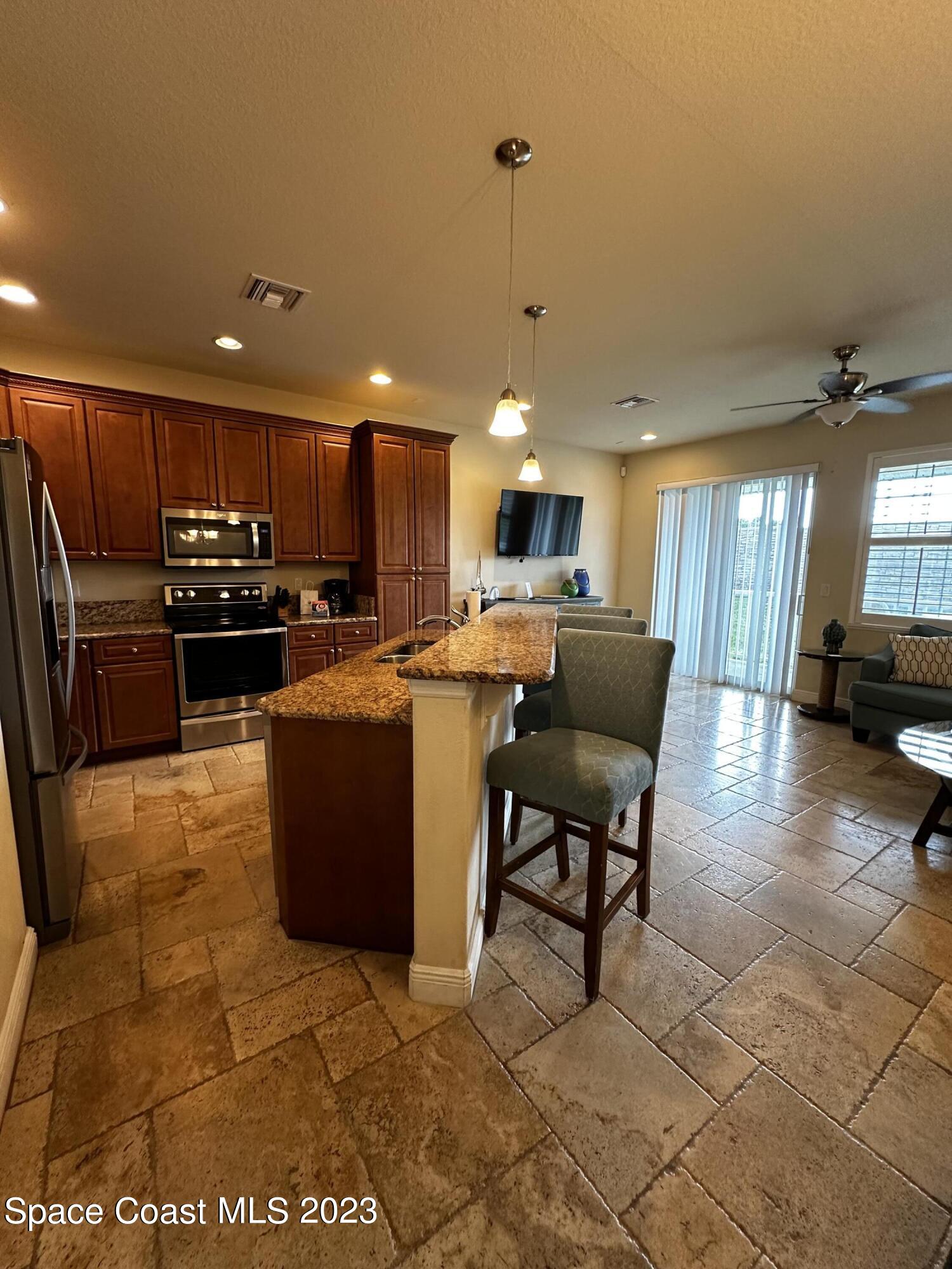 103 Parrotfish Lane, Unit 101 Merritt Island, FL 32953 - Photo 5 of 19 a kitchen with stainless steel appliances kitchen island granite countertop a sink and cabinets