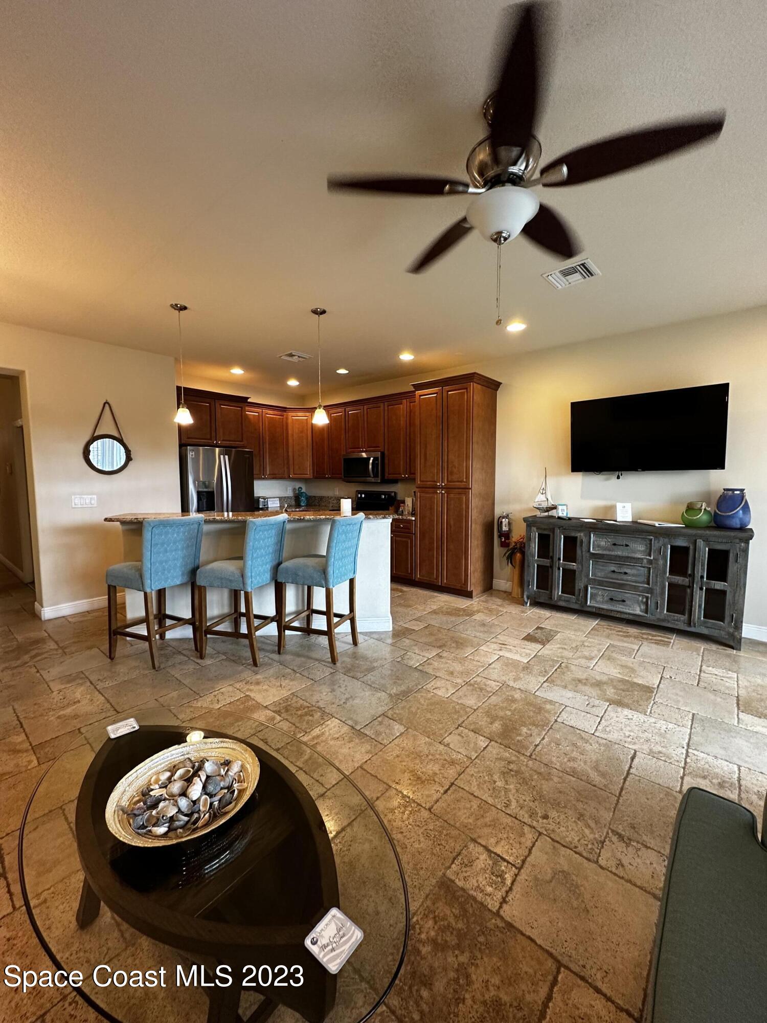 103 Parrotfish Lane, Unit 101 Merritt Island, FL 32953 - Photo 7 of 19 a living room with furniture and a flat screen tv with kitchen view