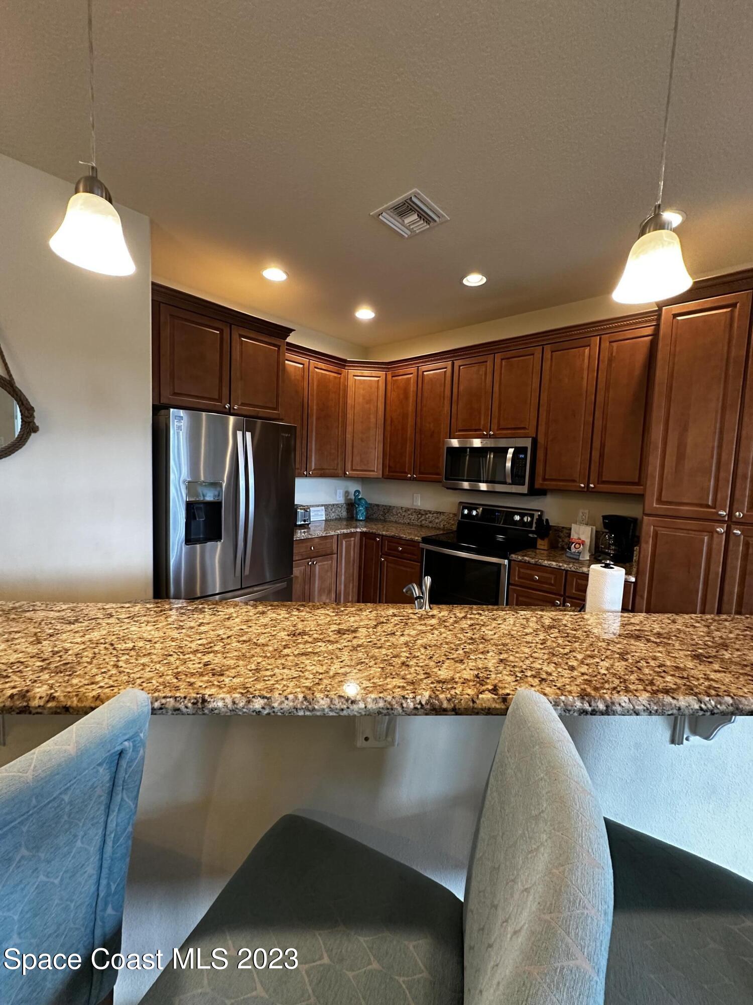 103 Parrotfish Lane, Unit 101 Merritt Island, FL 32953 - Photo 8 of 19 a kitchen with kitchen island granite countertop a stove and a sink