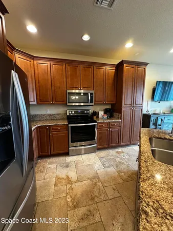 a kitchen with granite countertop a refrigerator and a stove top oven