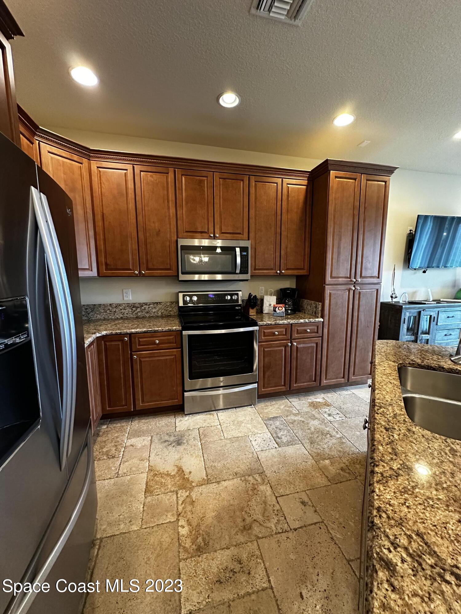 103 Parrotfish Lane, Unit 101 Merritt Island, FL 32953 - Photo 10 of 19 a kitchen with granite countertop a refrigerator and a stove top oven