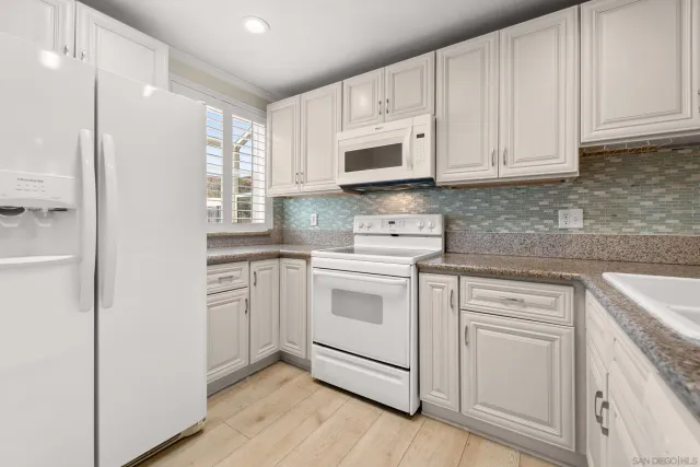 a kitchen with white cabinets and white appliances