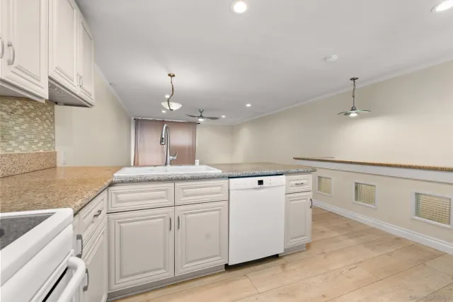a kitchen that has a lot of white cabinets and wooden floor