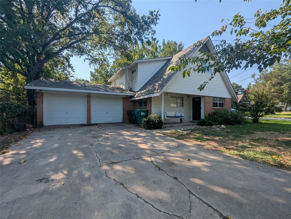 View of front of house with brick siding, an attached garage, driveway, and roof with shingles