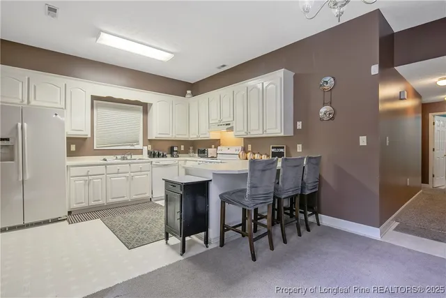 a kitchen with white cabinets and chairs