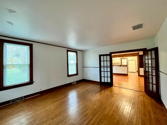 an empty room with wooden floor and windows