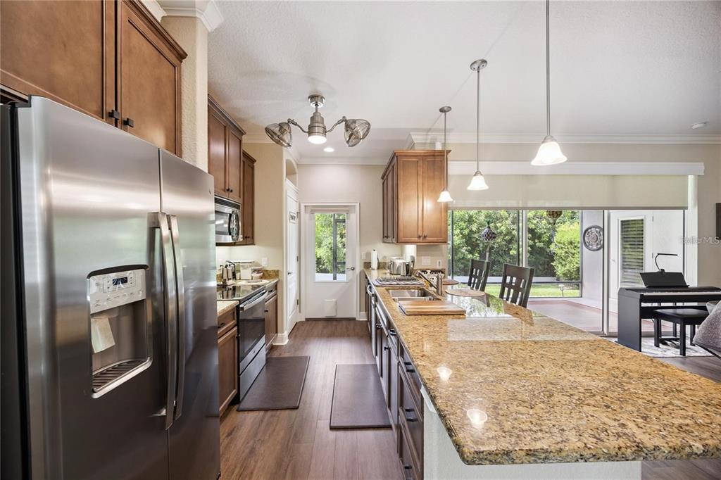 1923 Banning Beach Road Tavares, FL 32778 - Photo 10 of 44 a large kitchen with stainless steel appliances kitchen island granite countertop a refrigerator a oven a stove and a dining table with wooden floor