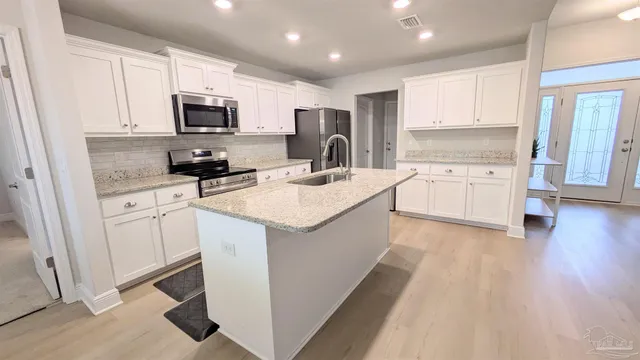 a kitchen with white cabinets sink and stainless steel appliances