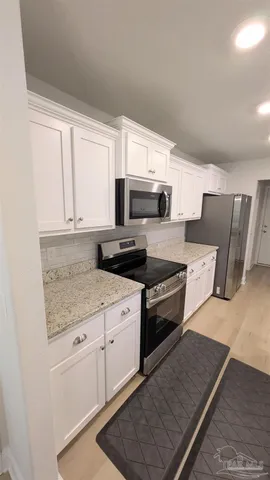 a large kitchen with granite countertop a stove top oven a sink a dining table and chairs