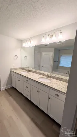 a bathroom with a granite countertop double vanity sink and mirror