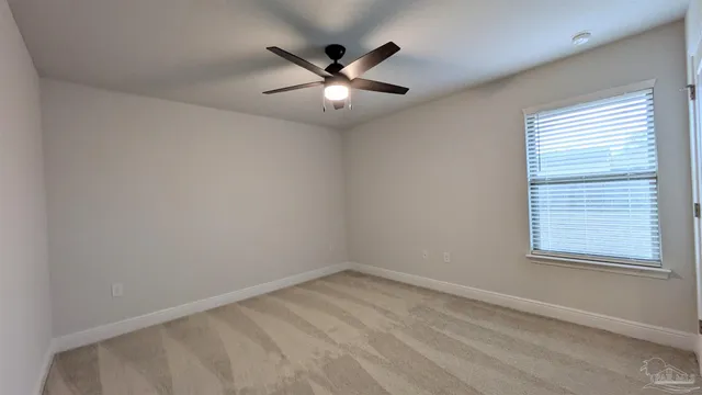 an empty room with window and ceiling fan