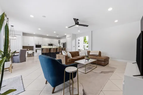 a living room with furniture kitchen view and a large window