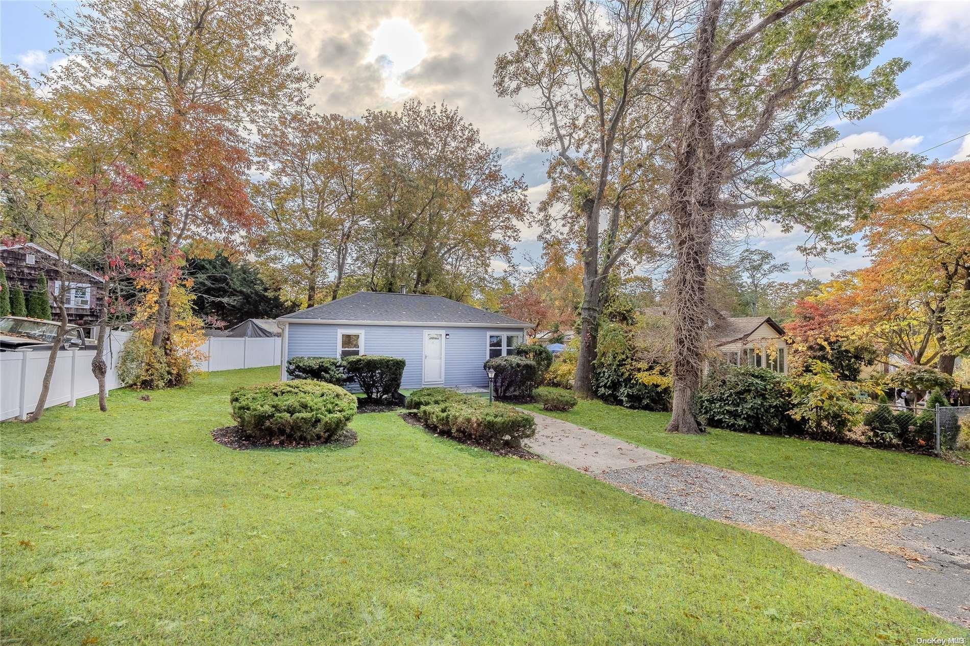 a view of a house with a big yard plants and large trees