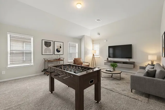 a living room with furniture a flat screen tv and a window