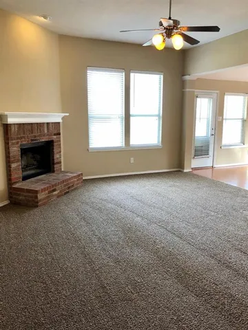 a view of an empty room with window fireplace and chandelier fan