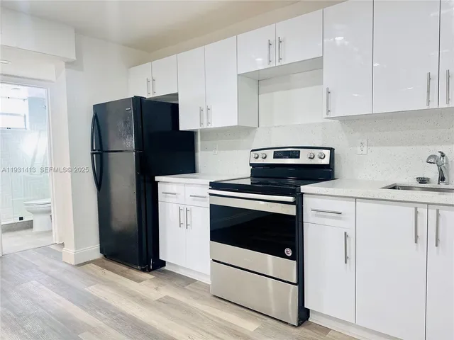 a kitchen with a refrigerator sink and cabinets