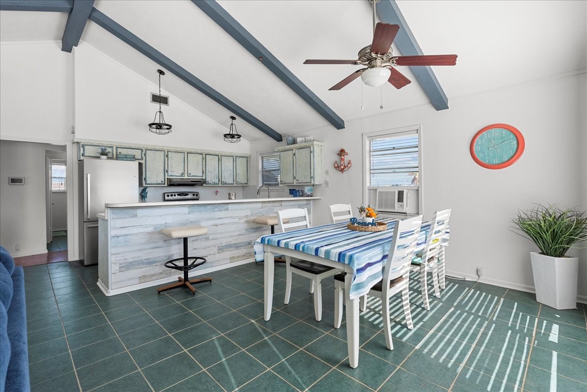 324 Shark Lane Surfside Beach, TX 77541 - Photo 14 of 49 Bright and airy kitchen and dining area with vaulted ceilings, exposed beams, and green tile flooring. Features a beachy color scheme, ceiling fan, breakfast bar, and plenty of natural light.