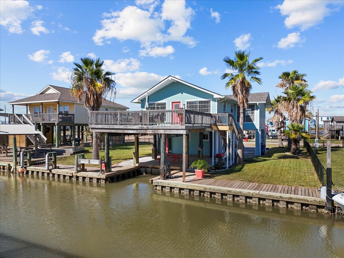 324 Shark Lane Surfside Beach, TX 77541 - Photo 3 of 49 This waterfront home features a raised structure with a spacious deck, perfect for enjoying canal views. It includes a well-maintained lawn with palm trees, direct water access, and a relaxed, coastal vibe.