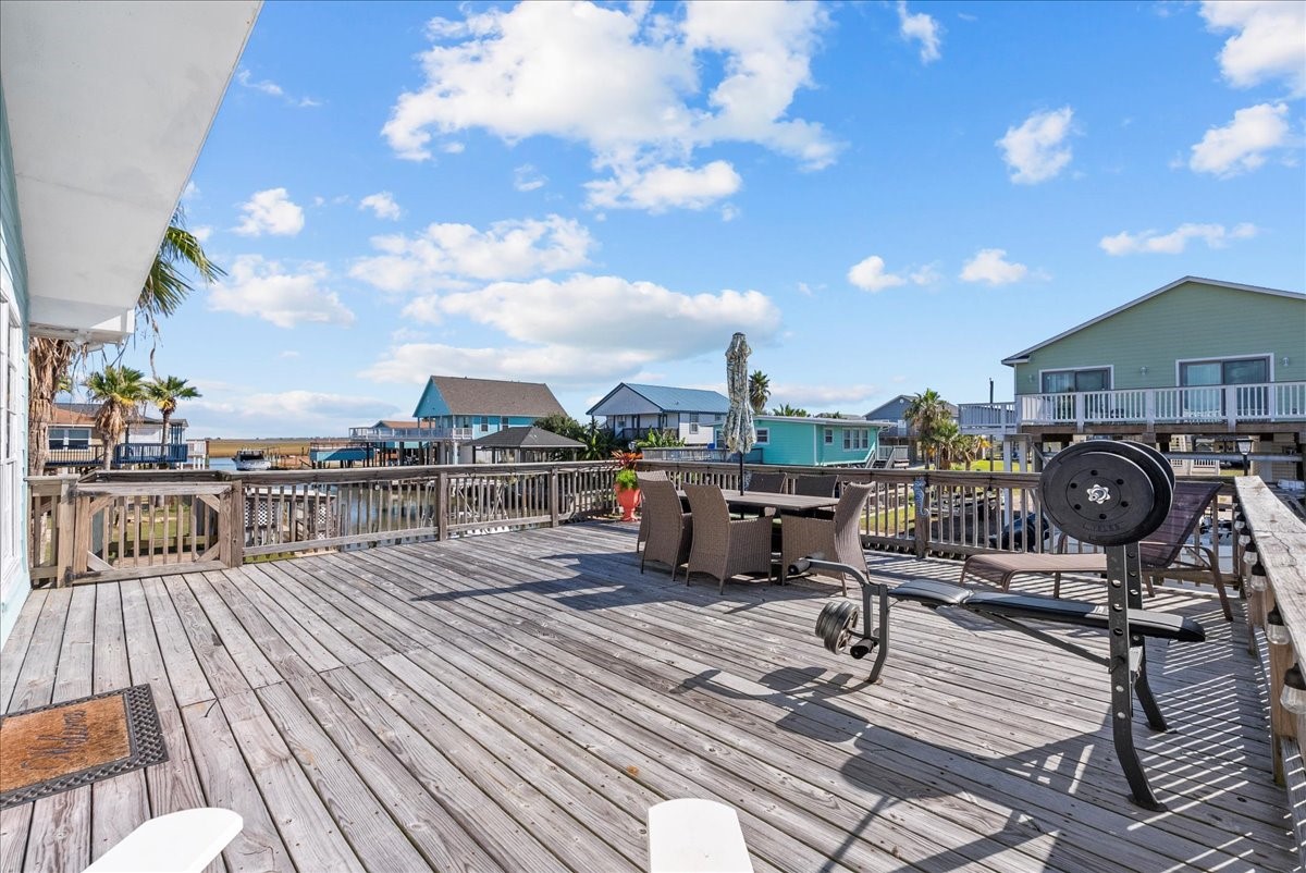 324 Shark Lane Surfside Beach, TX 77541 - Photo 31 of 49 Spacious waterfront deck with scenic views, perfect for outdoor dining and relaxation, featuring a dining set and exercise area. Ideal for enjoying coastal living.