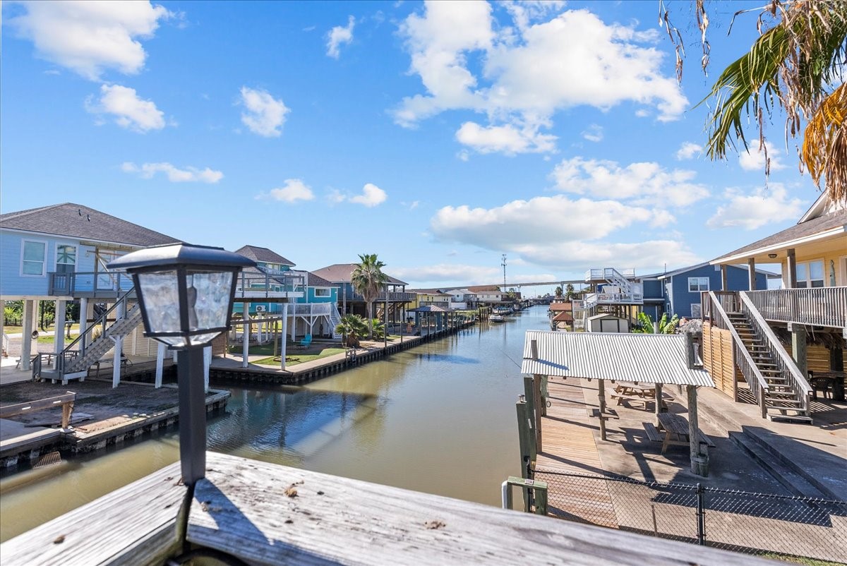 324 Shark Lane Surfside Beach, TX 77541 - Photo 32 of 49 This photo showcases a waterfront view with houses on stilts lining a tranquil canal, perfect for boating enthusiasts. The area features a clear blue sky and palm trees, offering a serene coastal ambiance.