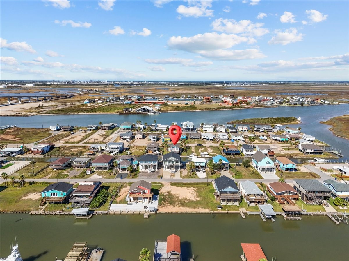 324 Shark Lane Surfside Beach, TX 77541 - Photo 48 of 49 This aerial photo showcases a charming waterfront community with a variety of houses, some featuring docks. The area is bordered by a calm waterway and open landscapes, offering potential for serene living and easy water access.