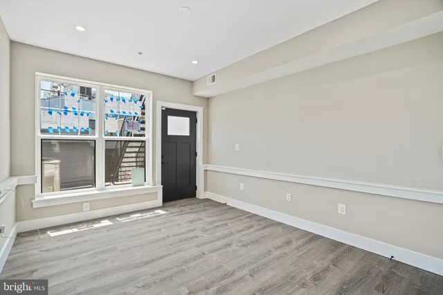 a view of an empty room with a window and wooden floor
