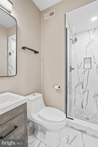 a white toilet sitting next to a bathroom sink and a shower