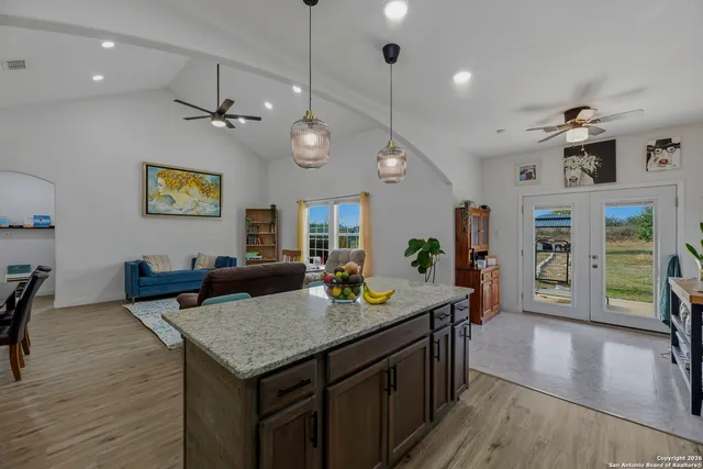 an open kitchen with granite countertop a stove dining table and chairs with wooden floor