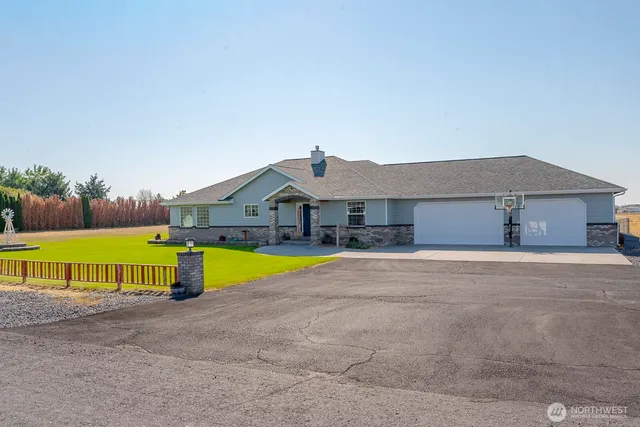 a front view of a house with a yard and a large tree