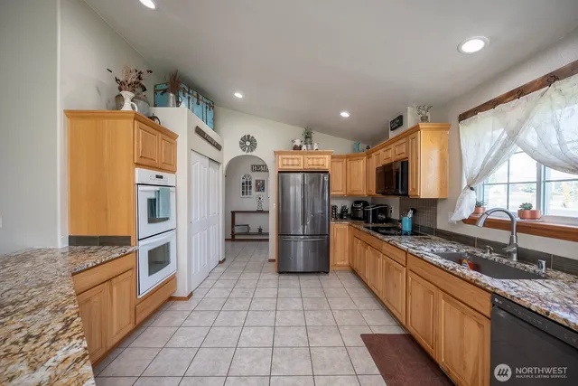 a large kitchen with stainless steel appliances granite countertop a large stove a sink dishwasher and a refrigerator