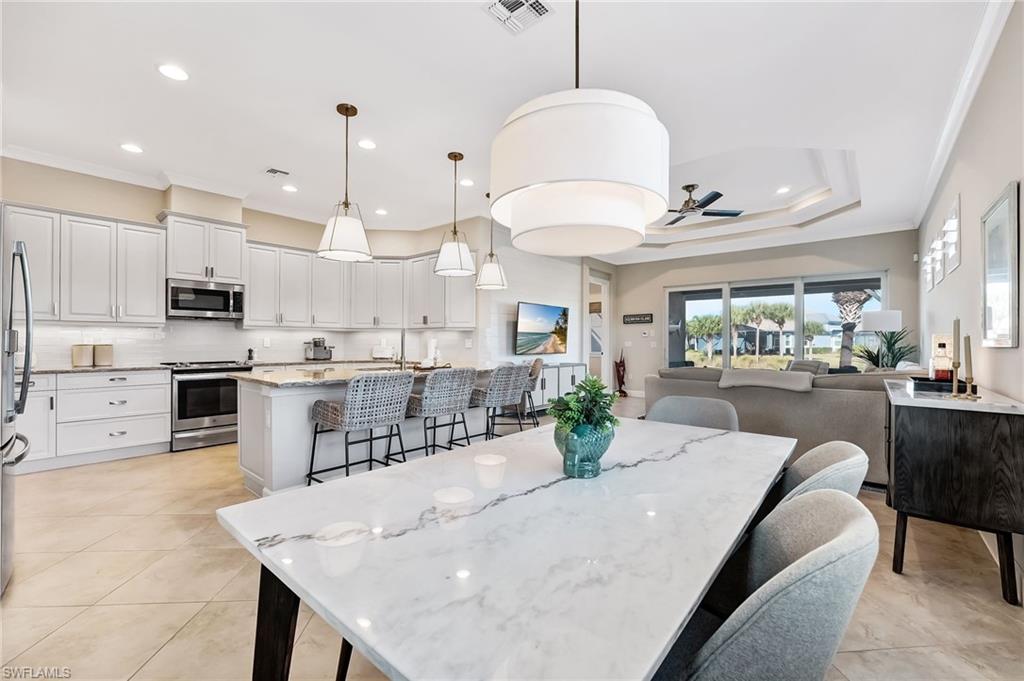 7002 Dominica Drive Naples, FL 34113 - Photo 11 of 45 Dining area with ornamental molding, ceiling fan, light tile patterned floors, recessed lighting, and a tray ceiling
