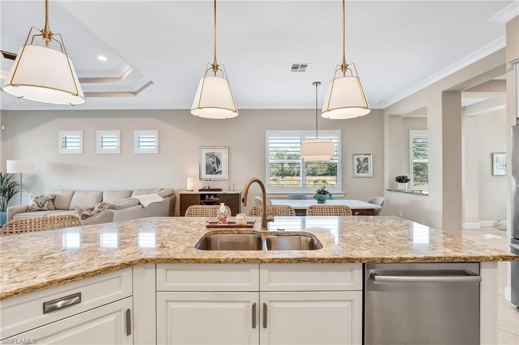 7002 Dominica Drive Naples, FL 34113 - Photo 45 of 45 Kitchen featuring open floor plan, dishwasher, light stone counters, hanging light fixtures, and white cabinetry