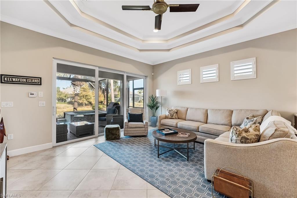 7002 Dominica Drive Naples, FL 34113 - Photo 18 of 45 Tiled living room with ornamental molding, ceiling fan, and a tray ceiling