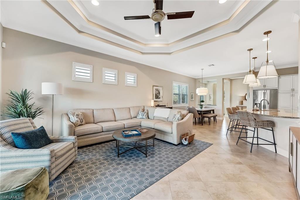 7002 Dominica Drive Naples, FL 34113 - Photo 19 of 45 Living room featuring ornamental molding, a ceiling fan, a tray ceiling, light tile patterned floors, and recessed lighting