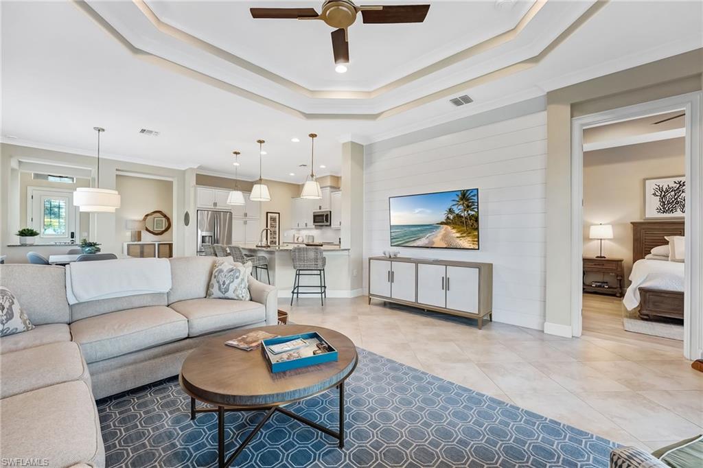 7002 Dominica Drive Naples, FL 34113 - Photo 21 of 45 Living room featuring ornamental molding, ceiling fan, a tray ceiling, and light tile patterned floors