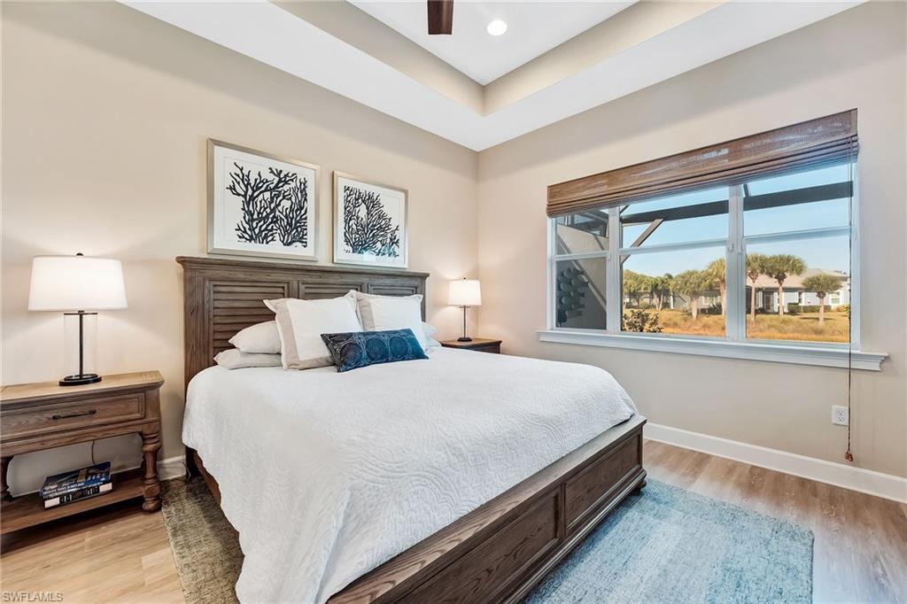 7002 Dominica Drive Naples, FL 34113 - Photo 22 of 45 Bedroom with light wood-style flooring, a ceiling fan, and a tray ceiling