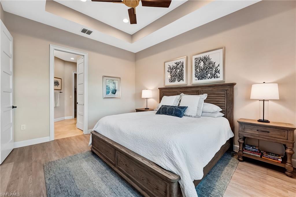 7002 Dominica Drive Naples, FL 34113 - Photo 24 of 45 Bedroom featuring a raised ceiling, recessed lighting, a ceiling fan, light wood finished floors, and ensuite bathroom