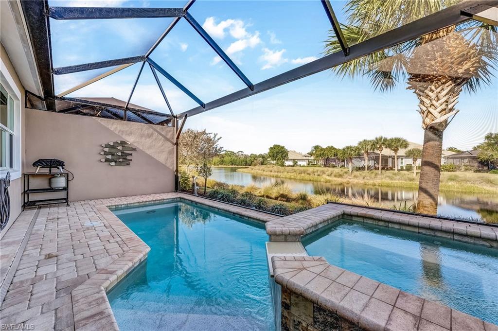 7002 Dominica Drive Naples, FL 34113 - Photo 38 of 45 View of swimming pool with a lanai, a patio area, a water view, a sunroom, and a pool with connected hot tub
