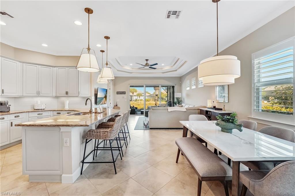 7002 Dominica Drive Naples, FL 34113 - Photo 44 of 45 Kitchen with decorative light fixtures, light stone countertops, open floor plan, a ceiling fan, and tasteful backsplash