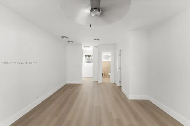 a view of a room with wooden floor and a ceiling fan