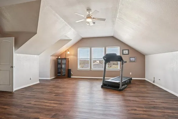 a view of a room with wooden floor gym equipment and a large window