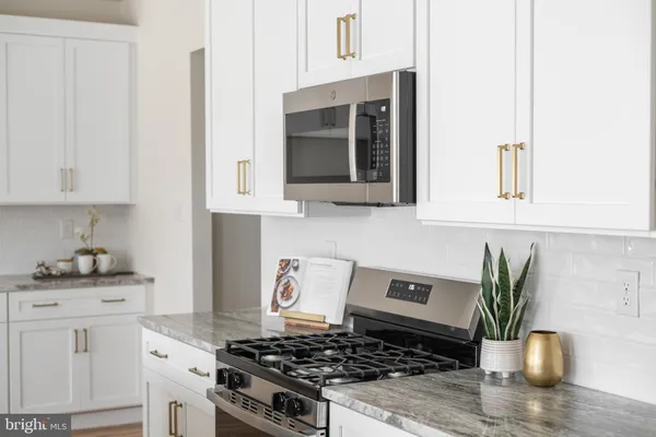 a kitchen with stainless steel appliances kitchen island granite countertop a stove a sink and a white cabinets
