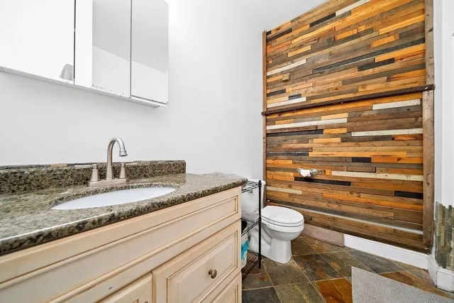 a bathroom with a granite countertop toilet sink and mirror