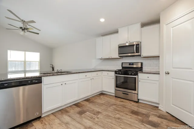 a kitchen with stainless steel appliances granite countertop a stove a sink and white cabinets