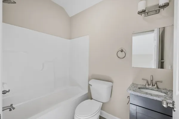 a bathroom with a granite countertop bathtub sink vanity mirror and toilet