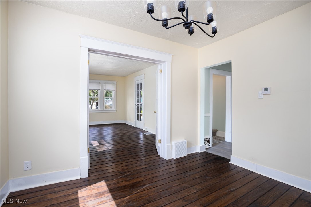 555 Brittain Road Akron, OH 44305 - Photo 24 of 26 Unfurnished dining area featuring a chandelier, dark wood-type flooring, and a textured ceiling