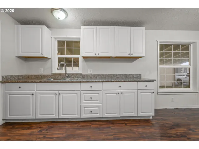 a kitchen with granite countertop white cabinets and sink